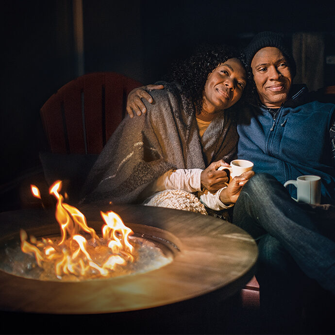 a-couple-cozied-up-around-the-fire-pit-at-night-time